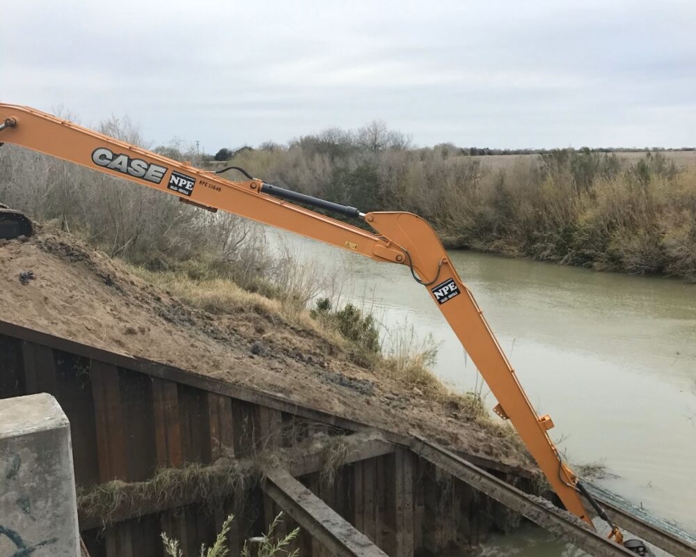 A large excavator tackling excavation work on a steep embankment, demonstrating its exceptional reach and maneuverability in challenging terrains. Bullock Construction's advanced dredging equipment is designed to access even the most hard-to-reach spaces, ensuring efficient performance in complex environments.