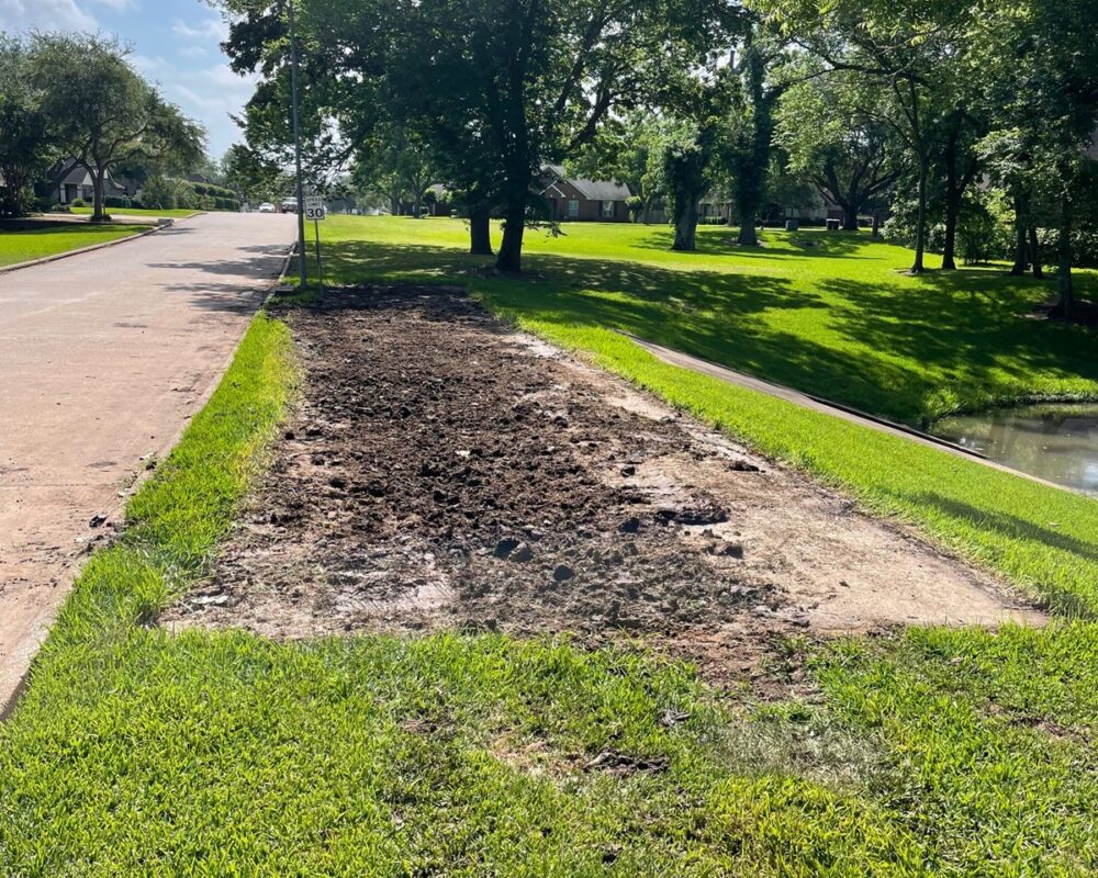 Prepared ground for a dewatering bag prior to the start of a residential dewatering project of an urban waterway.