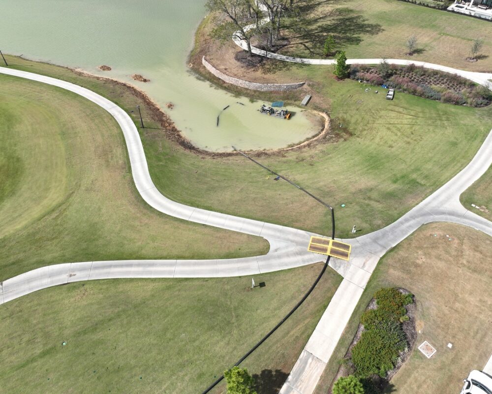 Drone view of hydraulic dredging barge in a golf course pond during sediment removal.