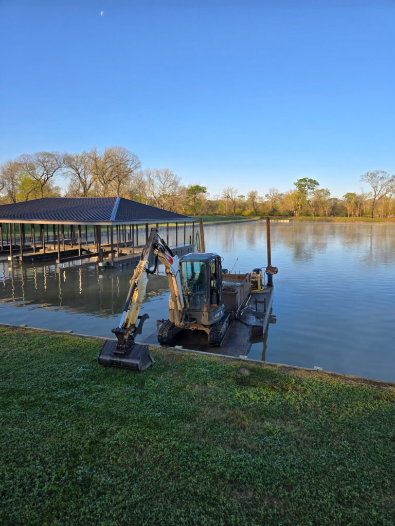 A small barge carrying a mechanical dredge and mud box for a marina restoration project.